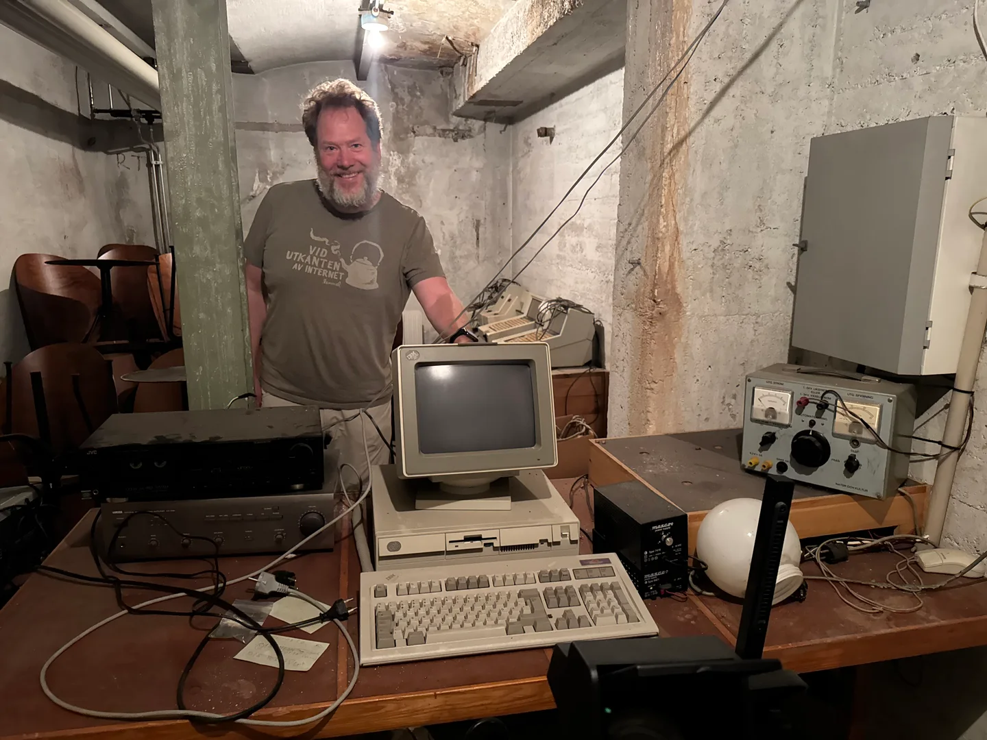 Erik Stenman standing beside an early IBM computer and other computing equipment